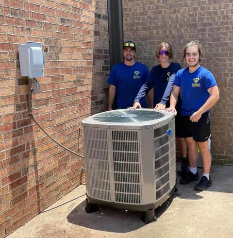 Three of our AC repair technicians posing with a newly installed air conditioner in Reno OK