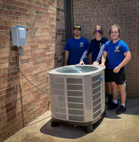 Three of our AC repair technicians posing with a newly installed air conditioner in Yukon OK