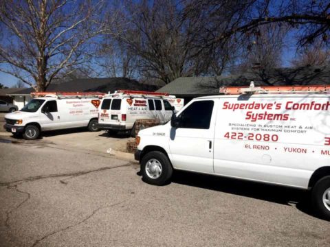 A fleet of Super Dave's Comfort Systems vans at an install at a customer's newly built home